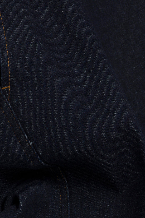 Dark indigo denim fabric with visible gold stitching along the seam.