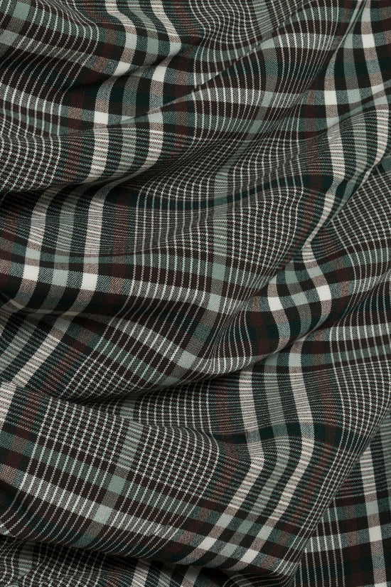 Green, black, and white plaid fabric with draped folds showing the dress's textured weave.