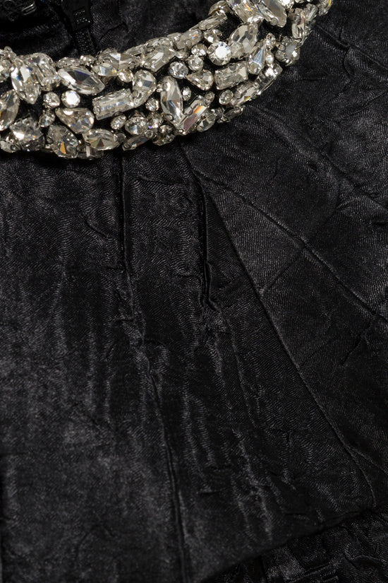 Black satin midi dress with crystal embellished neckline and pleated skirt detail.
