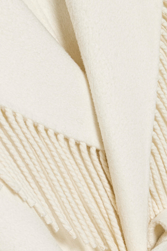 Cream-colored coat fabric with fringe trim along the edges and sleeves.