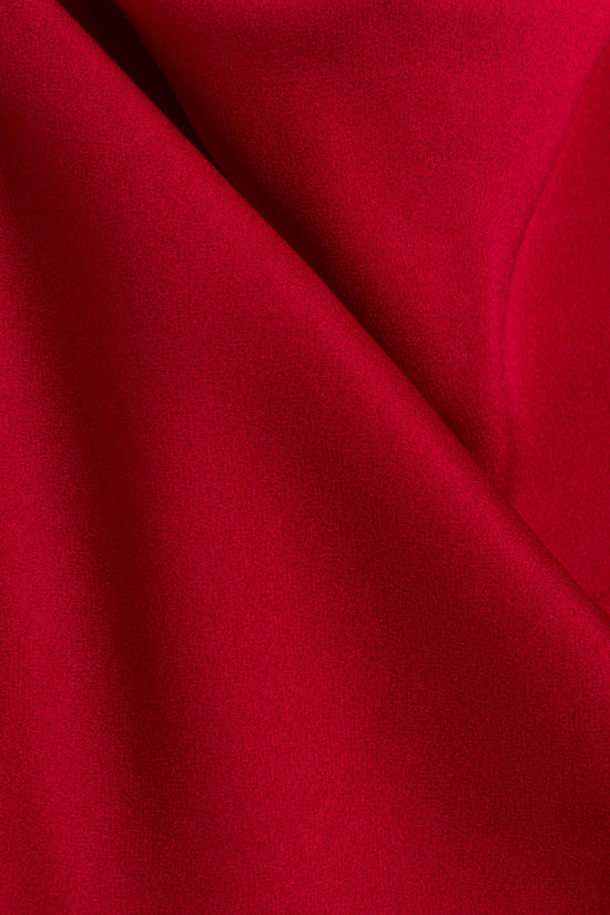 Red draped fabric with soft folds and flowing creases showing the gown's drape detail.