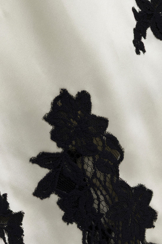 Cream fabric with black lace floral appliqués and textured embroidery details.