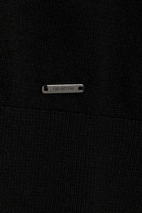 Black ribbed turtleneck with metal SIMKHAI brand plaque detail on chest.