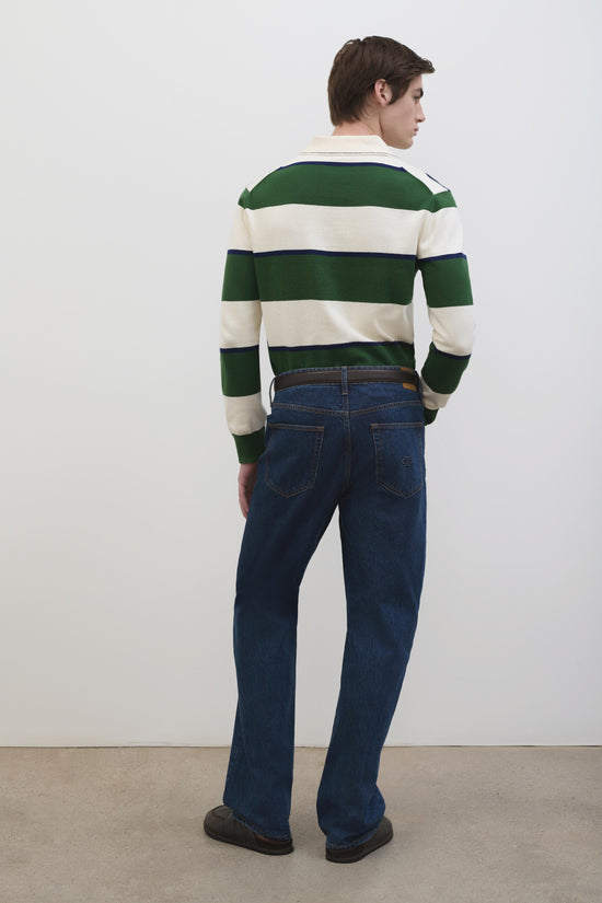 Man wearing green and cream horizontal striped popover with collared neckline and dark jeans.