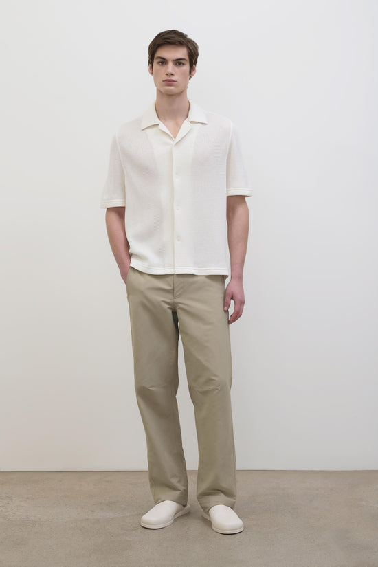 Cream waffle-textured short-sleeve button-up shirt with collar, shown on model wearing beige pants.