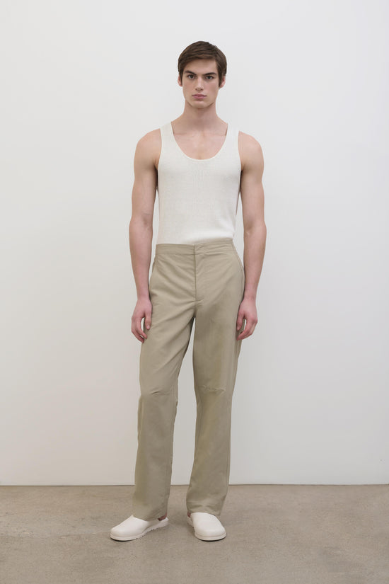 Man wearing beige Nicholas Tech Pant with straight leg fit and white slip-on shoes.