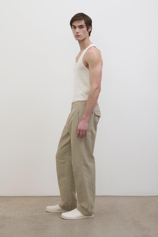 Man wearing beige tech pants with cargo pockets and a cream ribbed tank top.