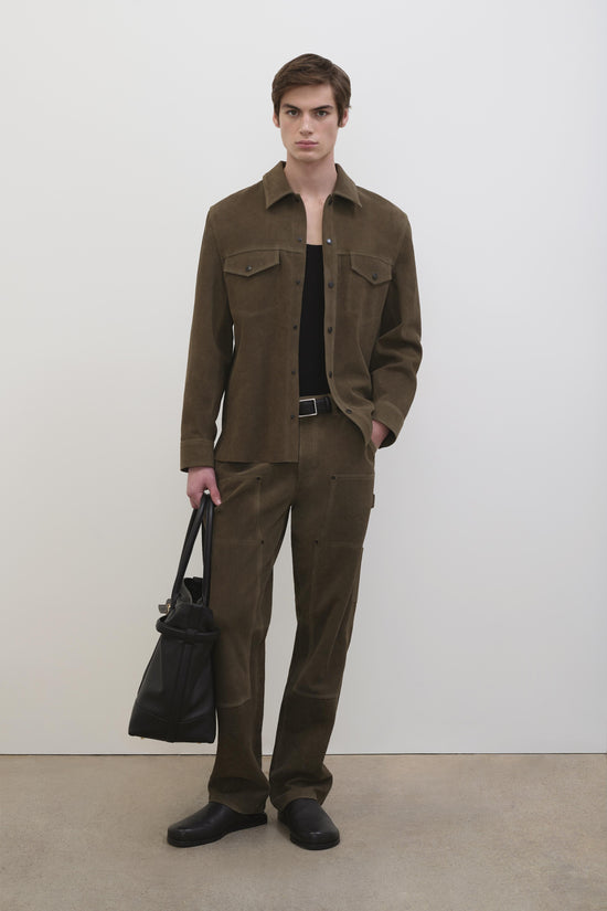 Olive-brown suede jacket with chest pockets and button front, styled with matching pants and black loafers.
