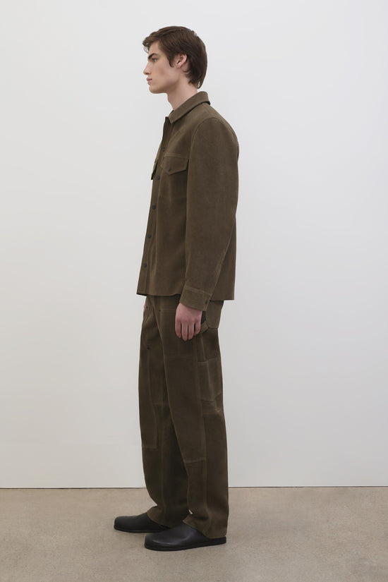 Olive suede utility jacket with chest pockets and button front, shown on model in profile view.