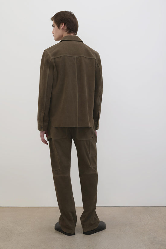Man wearing olive suede utility jacket and matching pants with cargo pockets, shown from back view.
