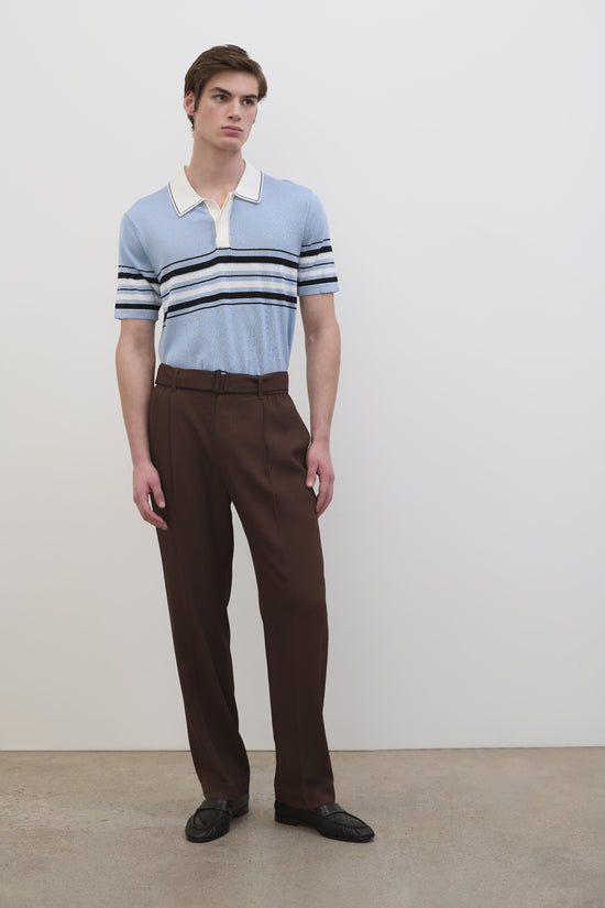 Man wearing light blue cotton knit popover with white collar and navy stripe trim, paired with brown trousers.