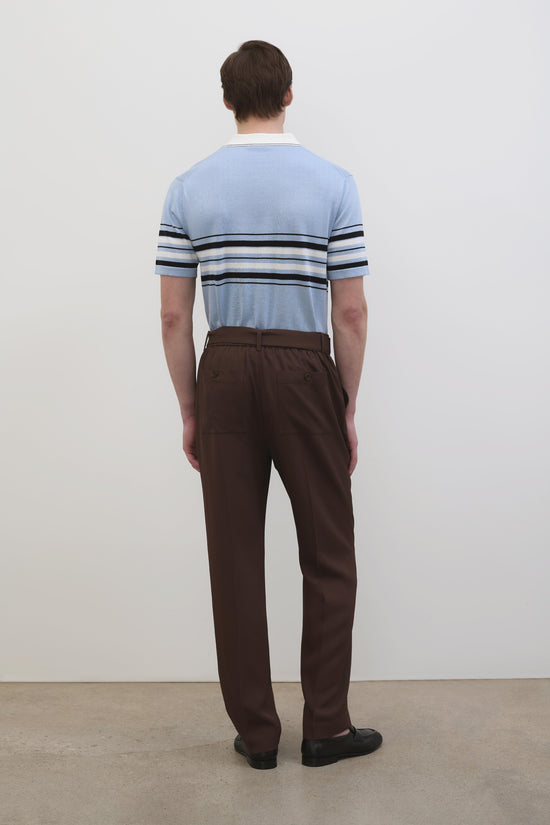 Light blue cotton knit popover with black and white horizontal stripes across chest, worn with brown trousers.