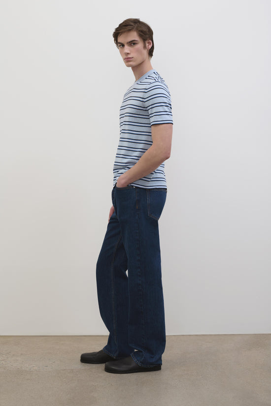 Men's short-sleeve tee with blue and navy horizontal stripes, shown styled with dark denim jeans.