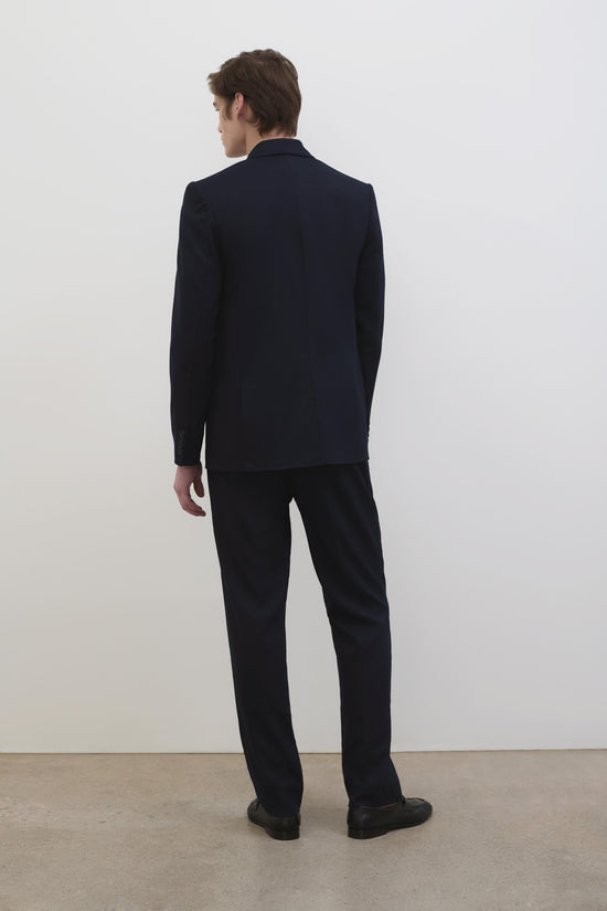 Black straight-leg trousers with flat front, shown from back on male model wearing navy shirt.