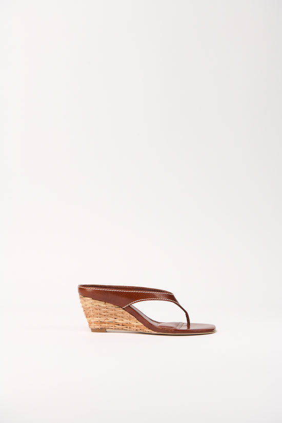 Brown leather thong wedge sandal with woven rattan wedge heel, shown in profile view.