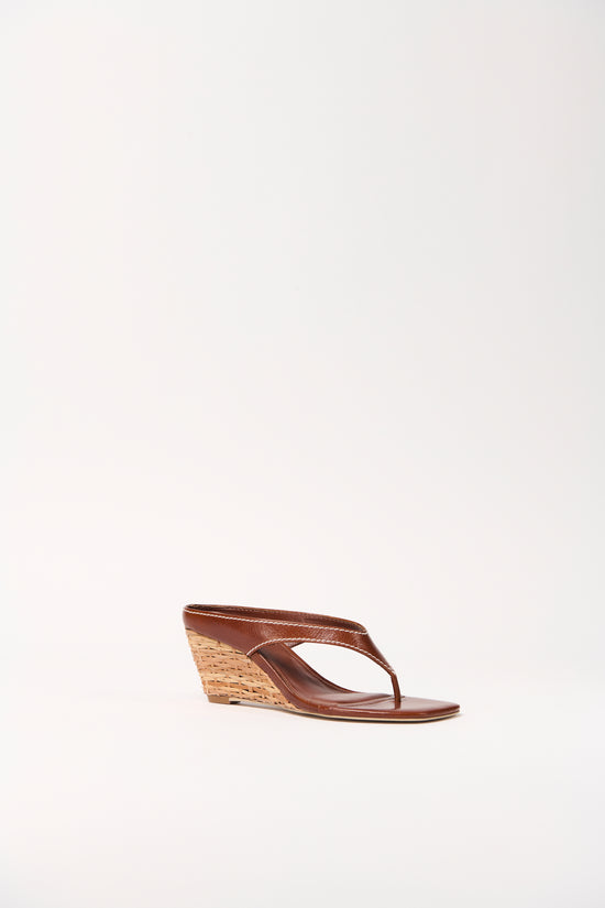 Brown leather thong wedge sandal with woven cork wedge heel, shown in side profile.