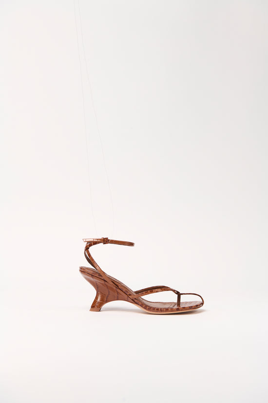 Brown leather strappy wedge sandal with toe-thong design and ankle buckle closure.