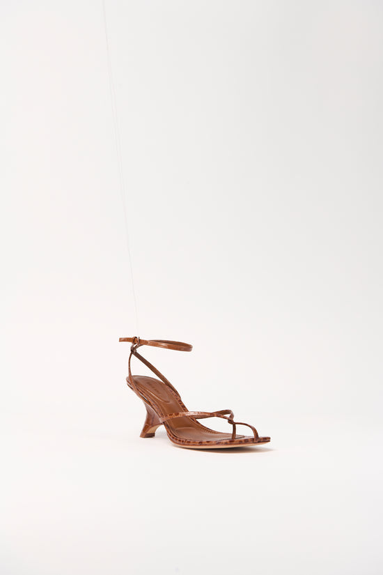 Tan leather strappy wedge sandal with ankle buckle closure and curved wedge heel.