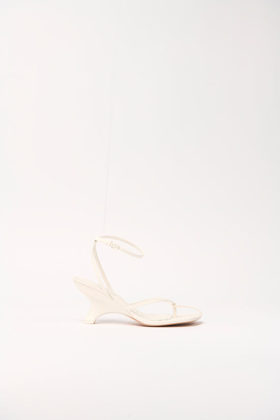 Cream leather strappy wedge sandal with ankle strap and open toe design.