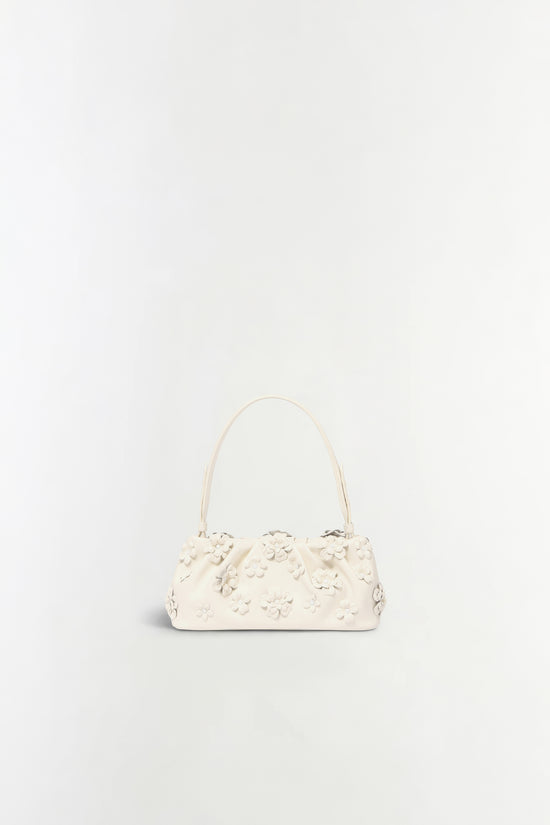 Cream leather shoulder bag with dimensional flower appliqués across the body and curved handles.