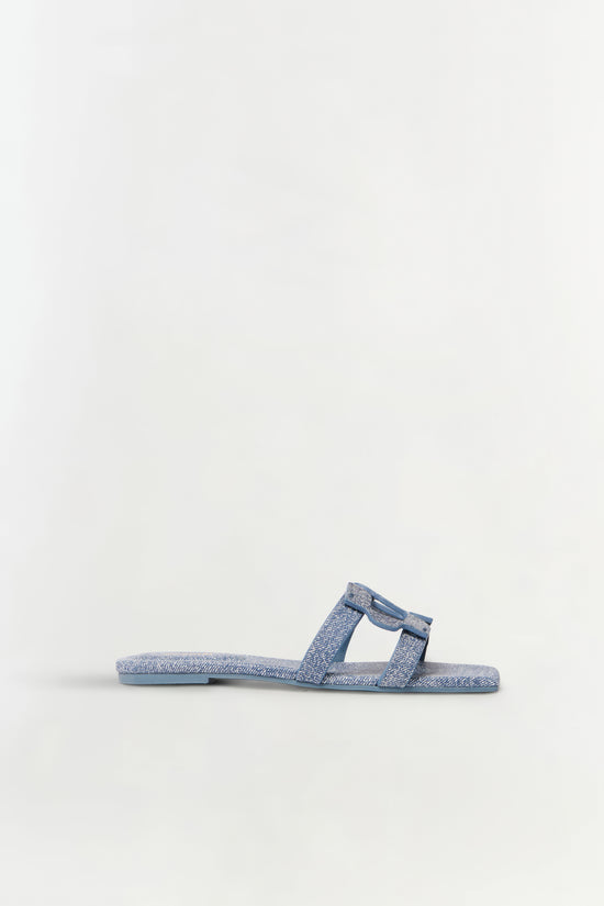 Blue denim flat slide sandal with monogram pattern and leather trim shown in profile view.