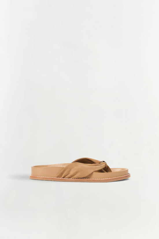 Tan suede flat sandal with twisted knotted strap detail and light sole, shown in side view.