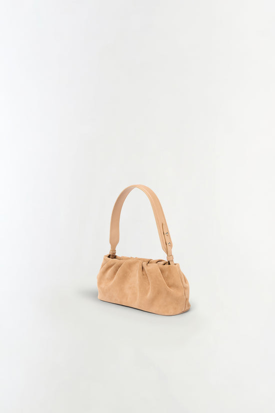 Tan suede shoulder bag with gathered front panel and single adjustable strap.