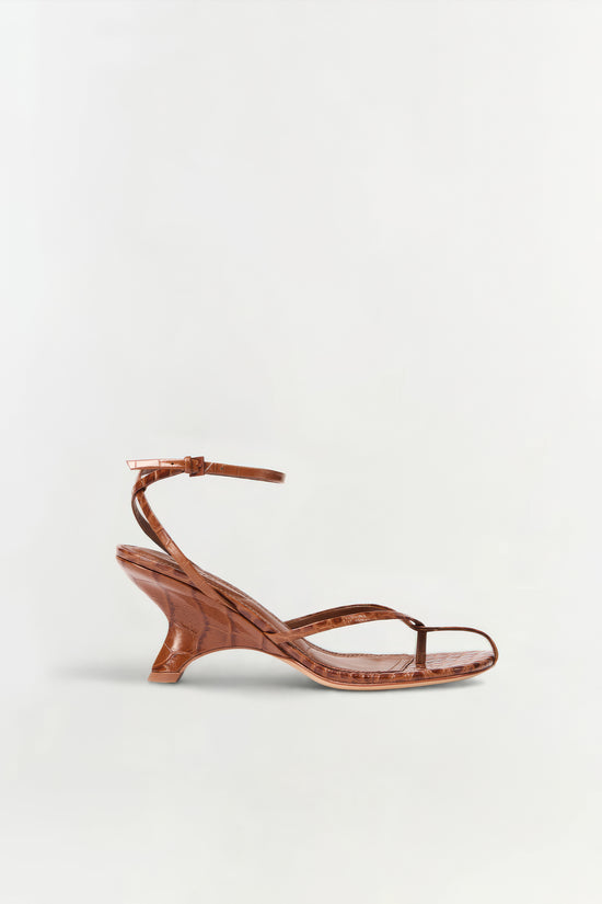 Brown leather strappy wedge sandal with ankle buckle and curved wedge heel, shown in profile view.