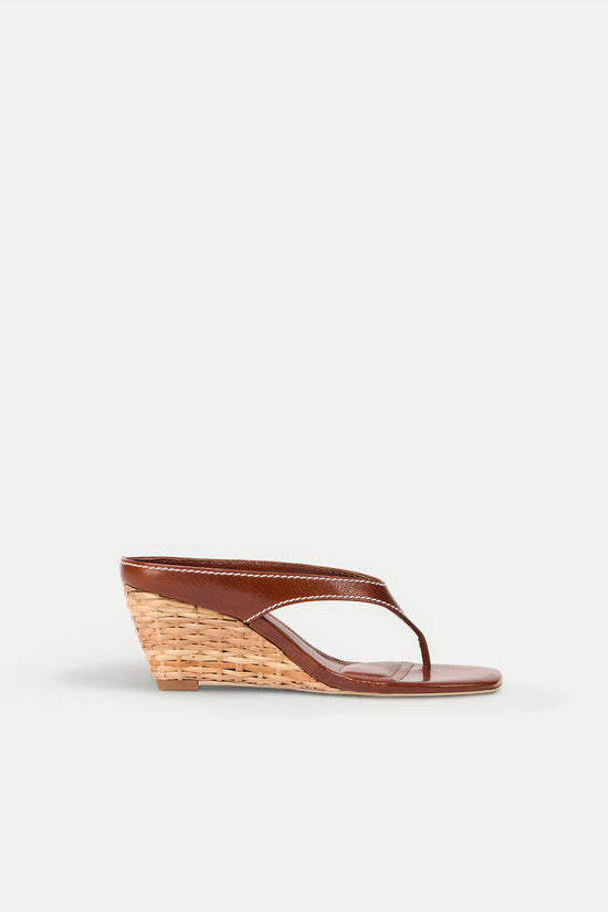 Brown leather thong sandal with woven rattan wedge heel, shown in side profile.