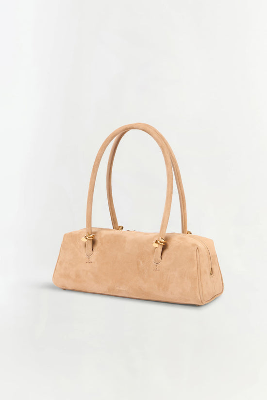 Beige suede shoulder bag with dual handles and gold-tone hardware on a neutral background.