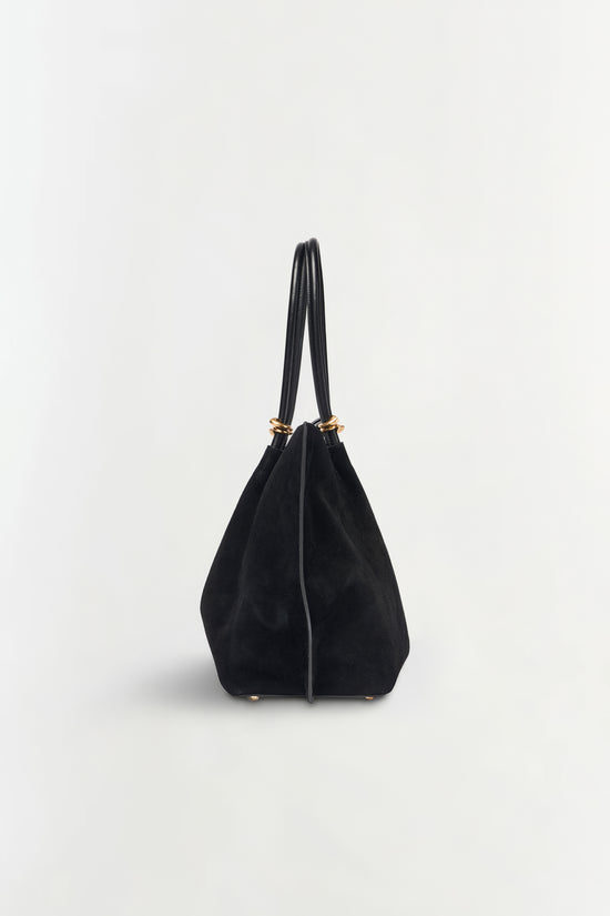 Black suede tote bag with dual leather handles and gold-tone hardware at the top.