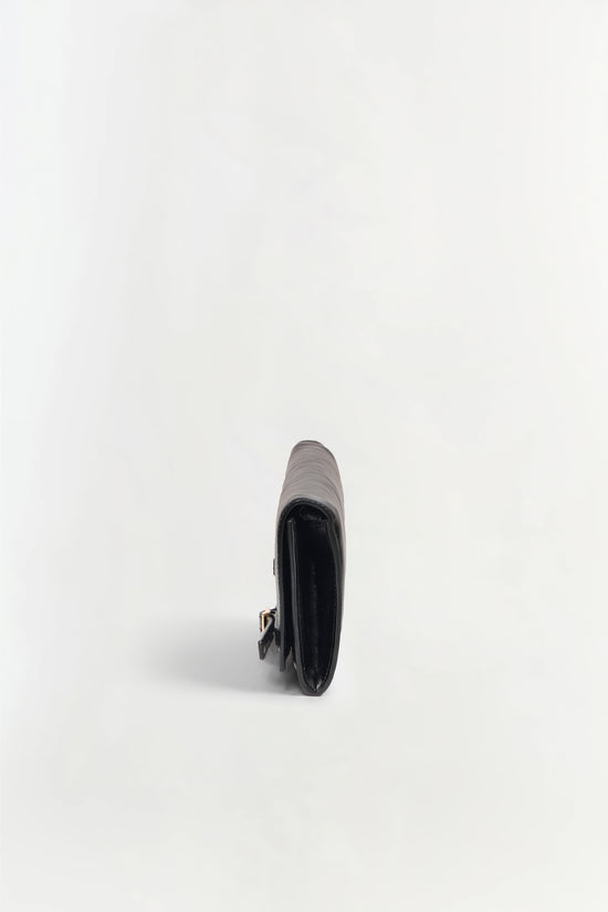 Black leather clutch with gray and white striped top panel and gold-toned clasp, shown from side angle.