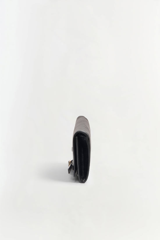 Black leather clutch with gray and white striped top panel and gold-toned clasp, shown from side angle.