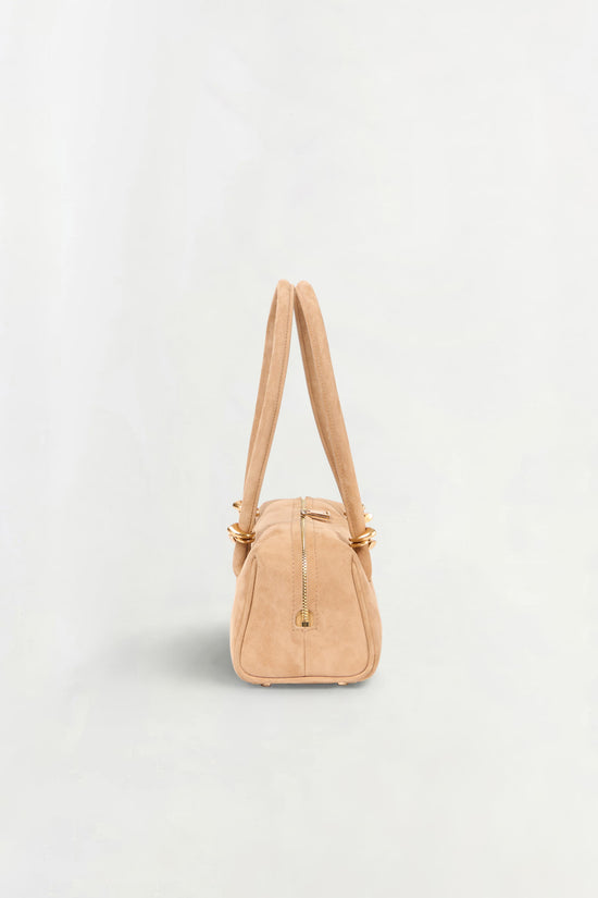 Tan suede shoulder bag with dual handles and gold-toned zipper detail on front.