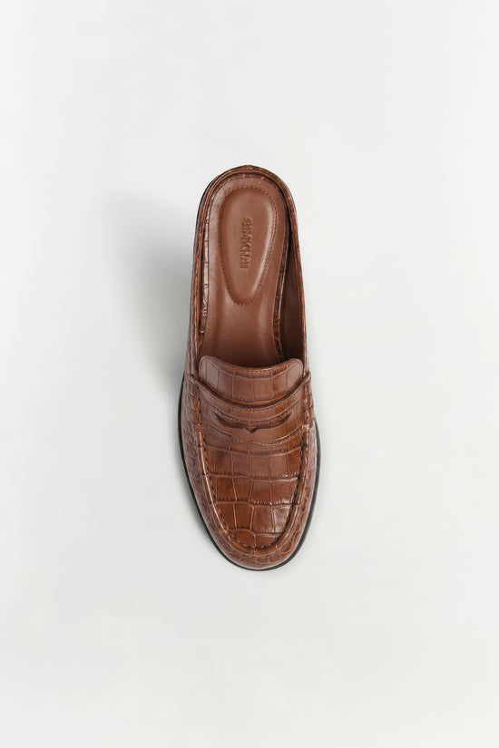 Brown crocodile-embossed leather loafer mule shown from above with visible interior sole.